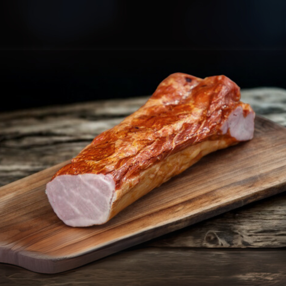Whole piece of smoked Canadian bacon with a deep amber smoked exterior on a wooden board