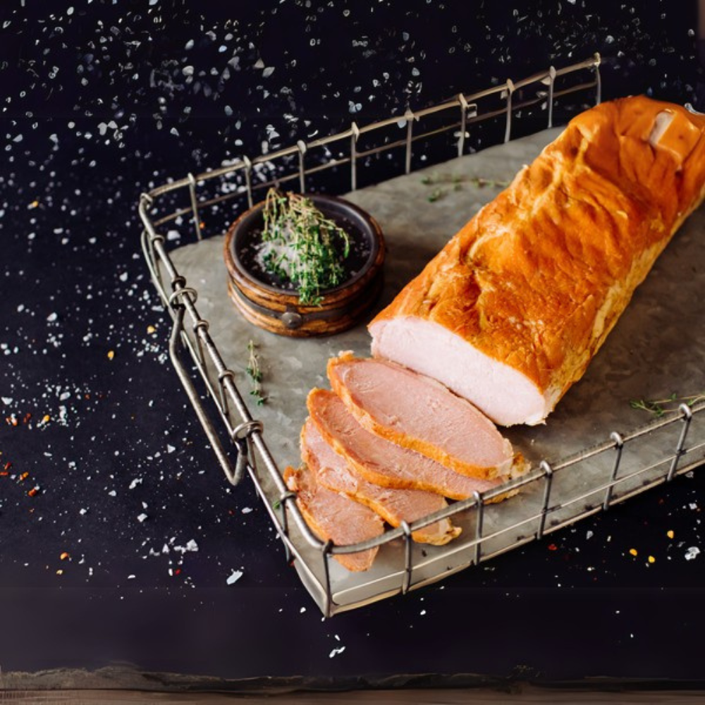 Smoked Canadian bacon with lean slices fanned out from the whole piece on a metal serving tray