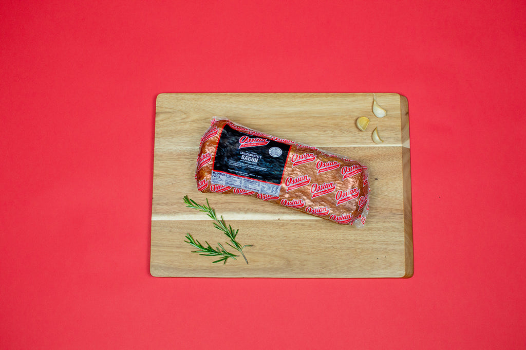 Ossian Canadian style bacon, vacuum sealed in its red Ossian package, on a wooden cutting board